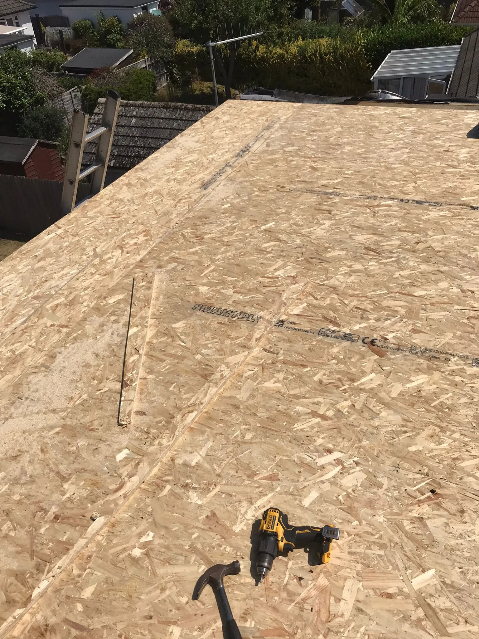 Newly installed OSB roof decking with construction tools on a residential roof.
