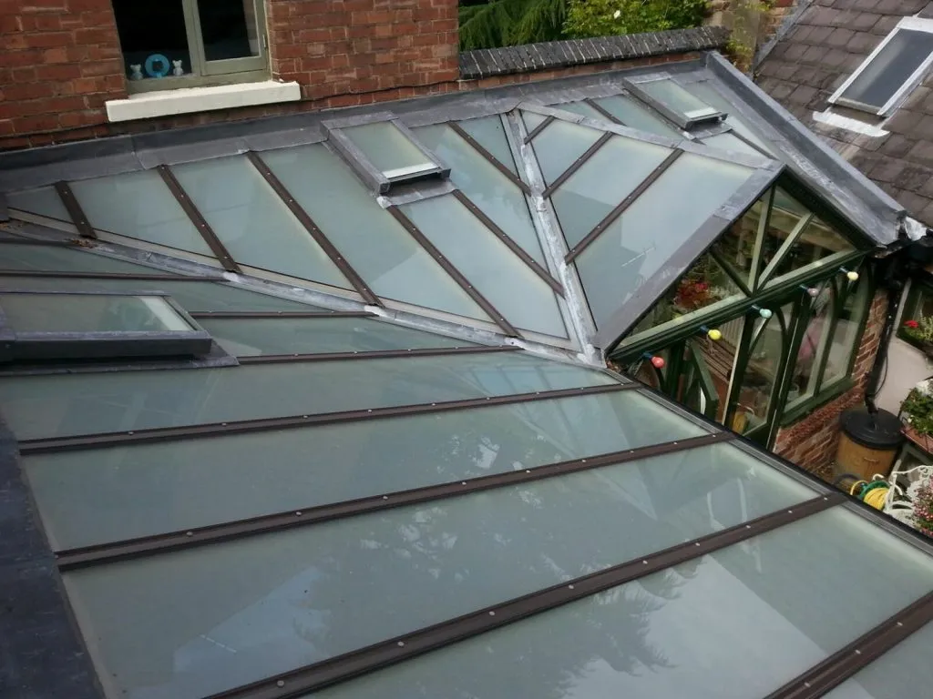 A large glass roof with multiple skylights and roof windows on a residential property.