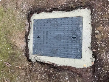 Drainage manhole cover set in fresh concrete surround