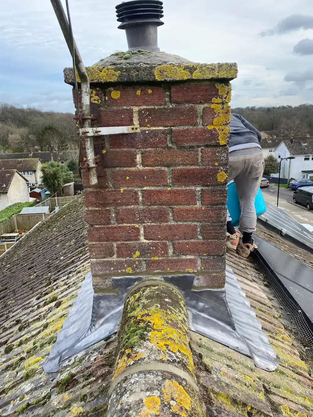 Roofer working on a chimney repair on a residential tiled roof