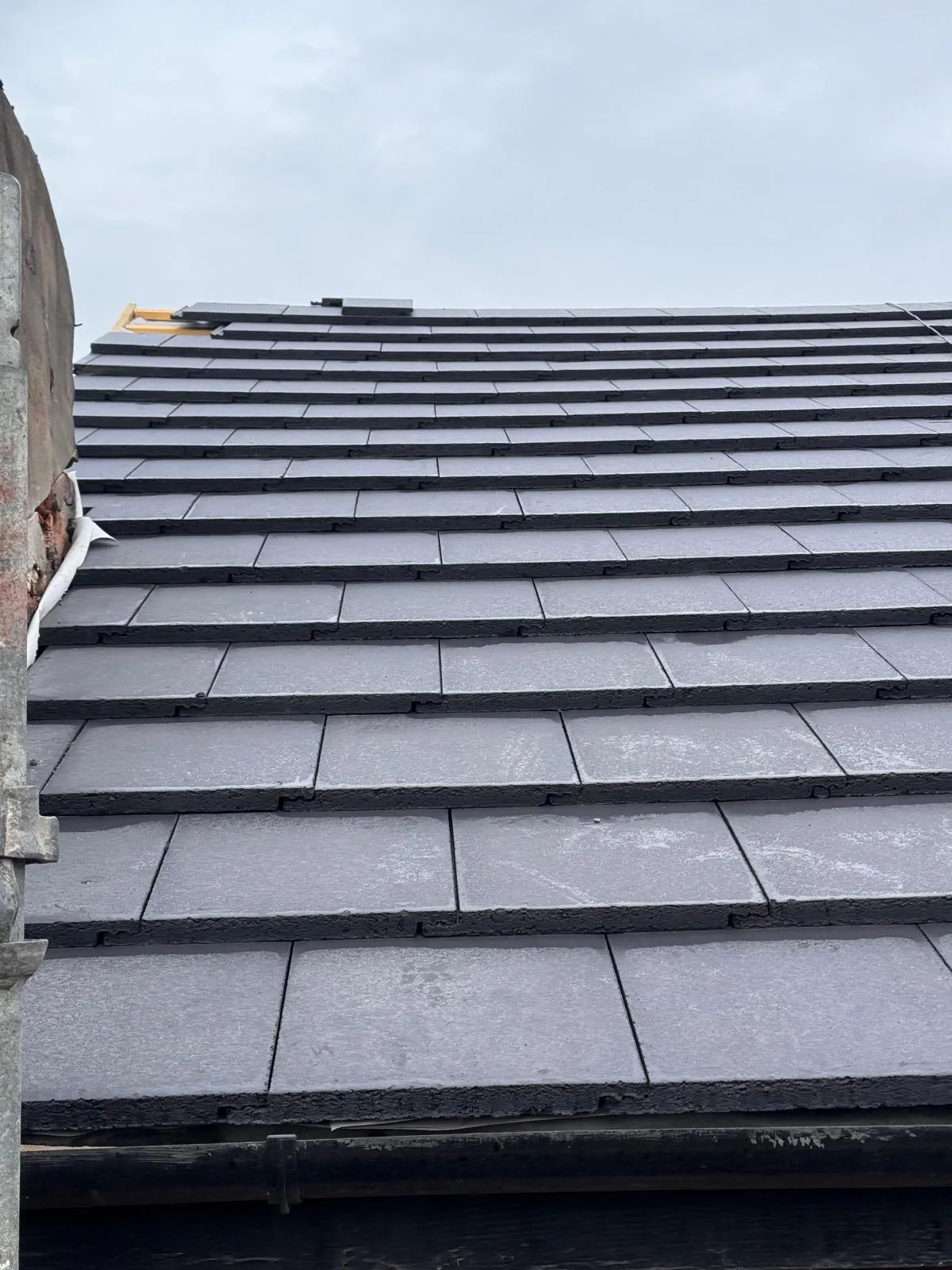 Newly installed dark grey tiled roof on a residential property