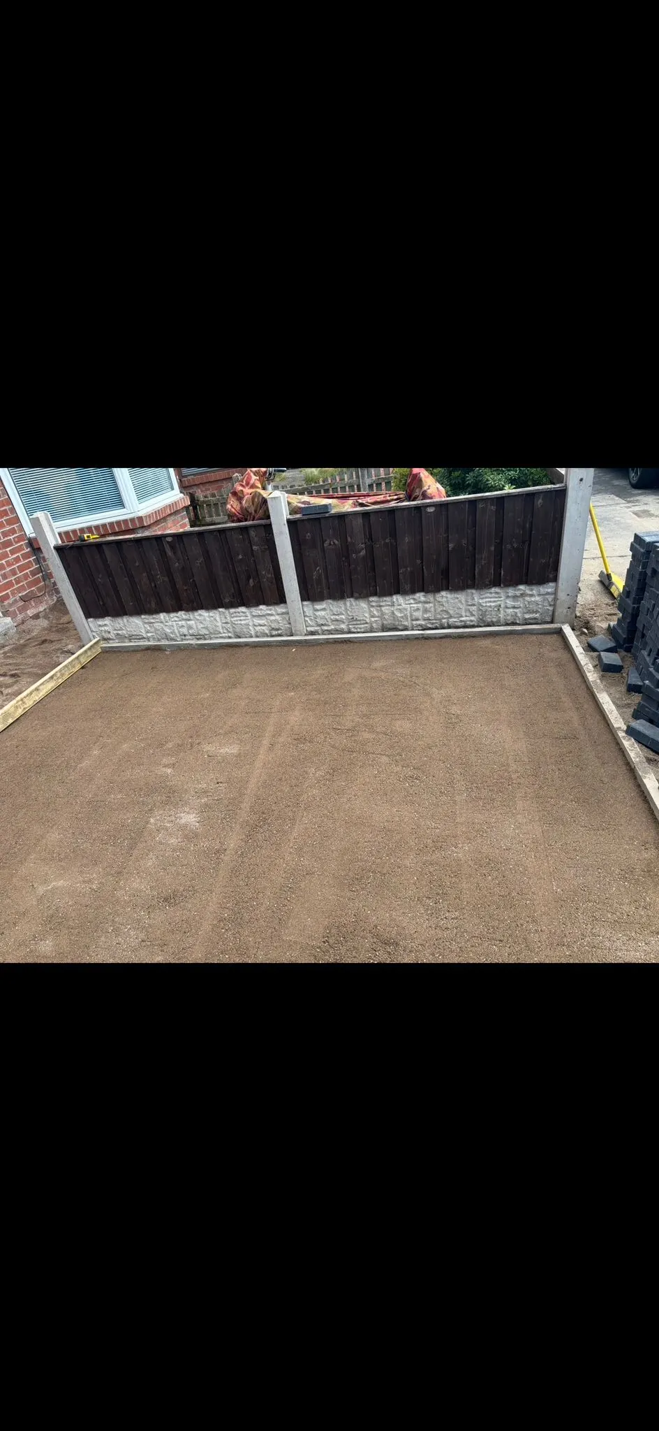 Base layer prepared for a new driveway or patio with paving blocks ready for installation.