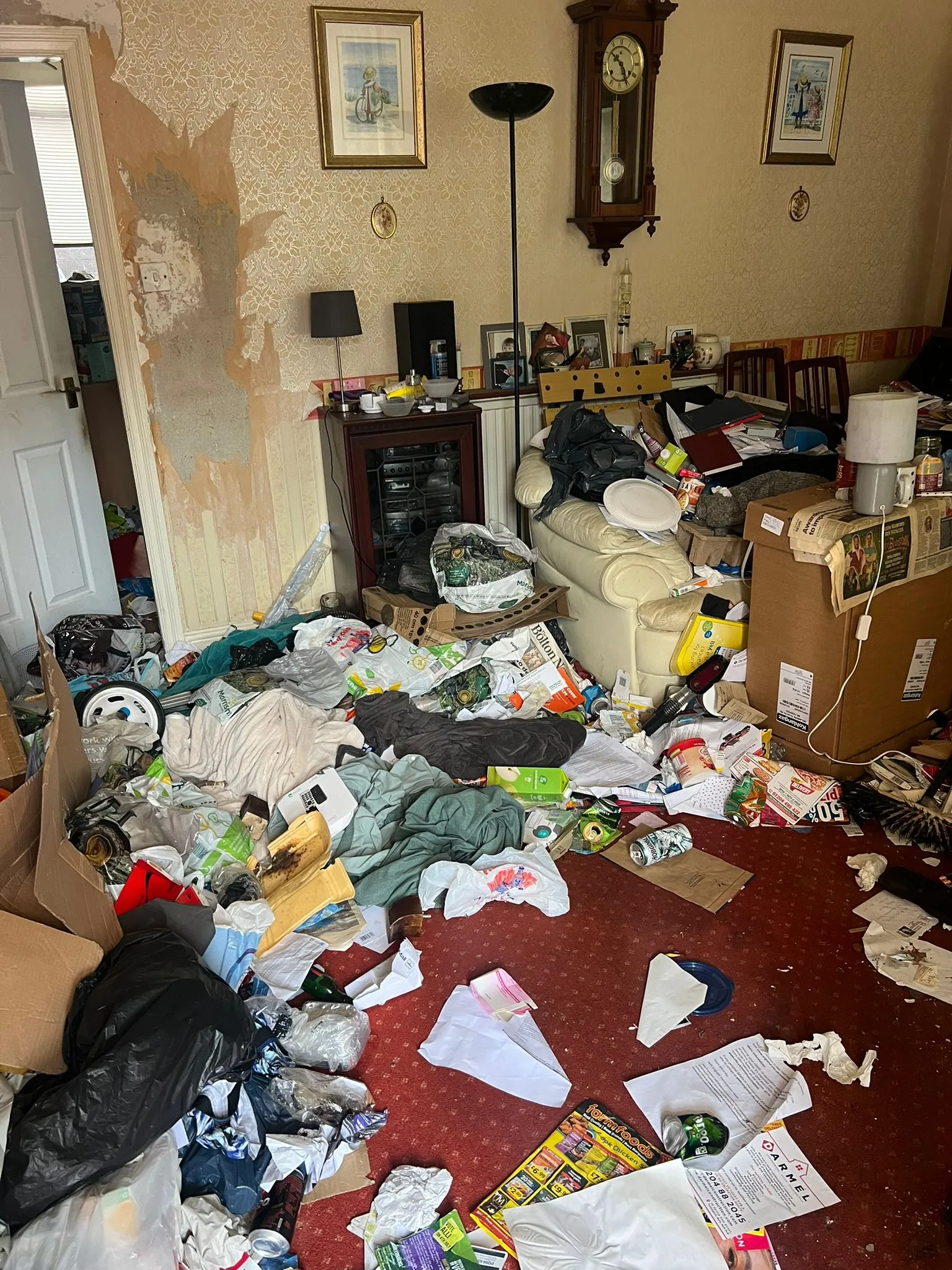 A heavily cluttered living room needing a professional hoarder or extreme house clearance service.