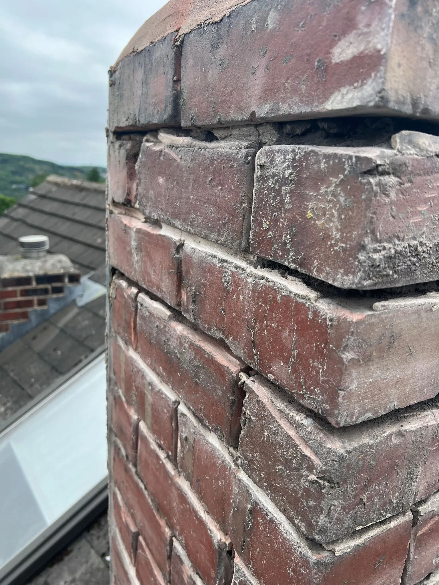Close-up of a brick chimney on a roof showing crumbling mortar, typical of chimney repair needs in Sheffield or the Peak District.