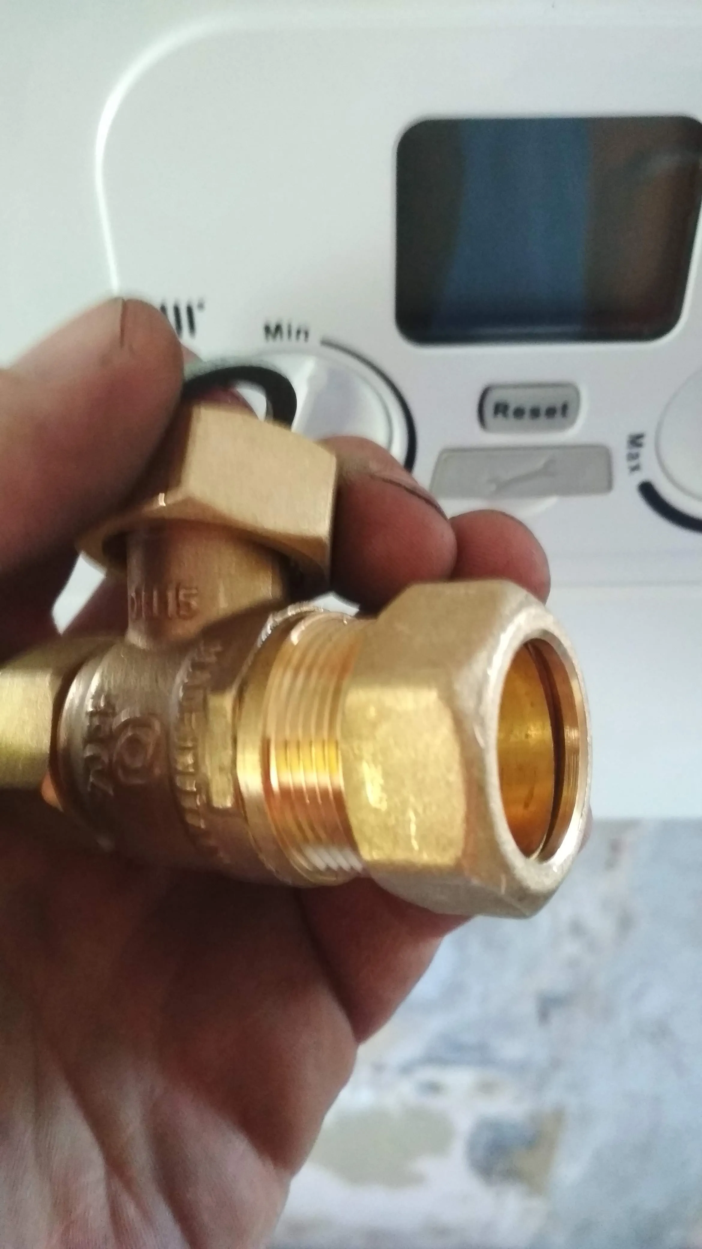A plumber holding a brass boiler fitting, ready for installation or repair.
