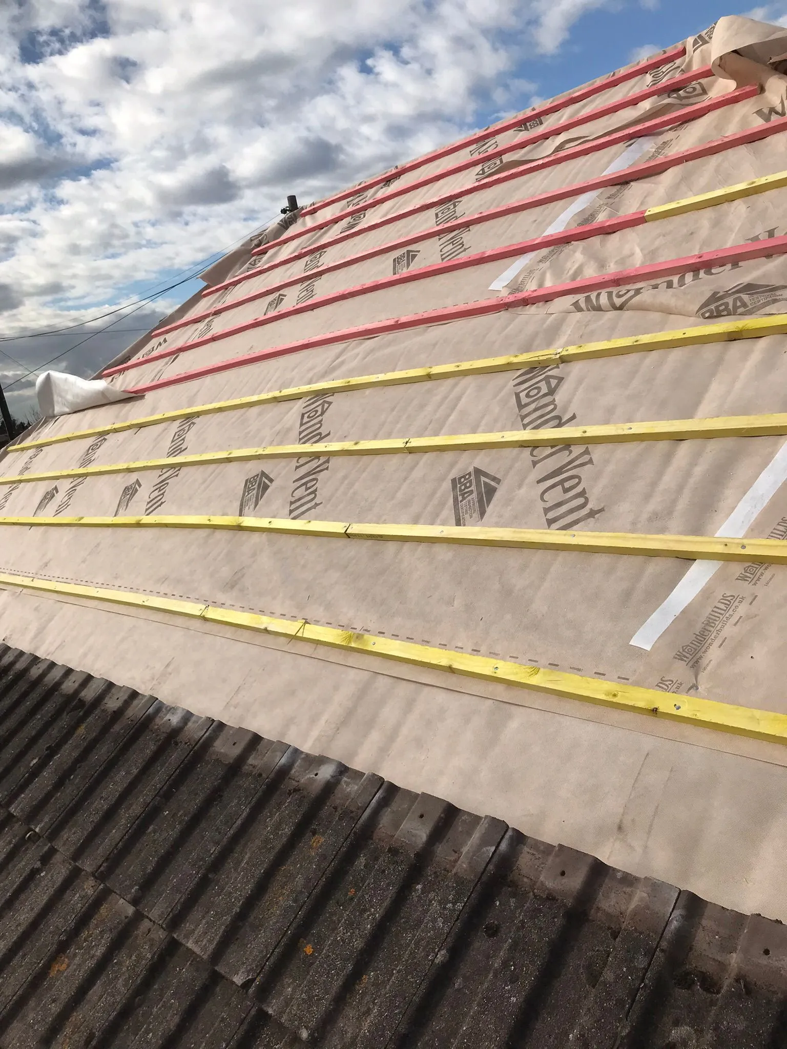 Pitched roof structure with roofing membrane and wooden battens installed, ready for roof tiles.