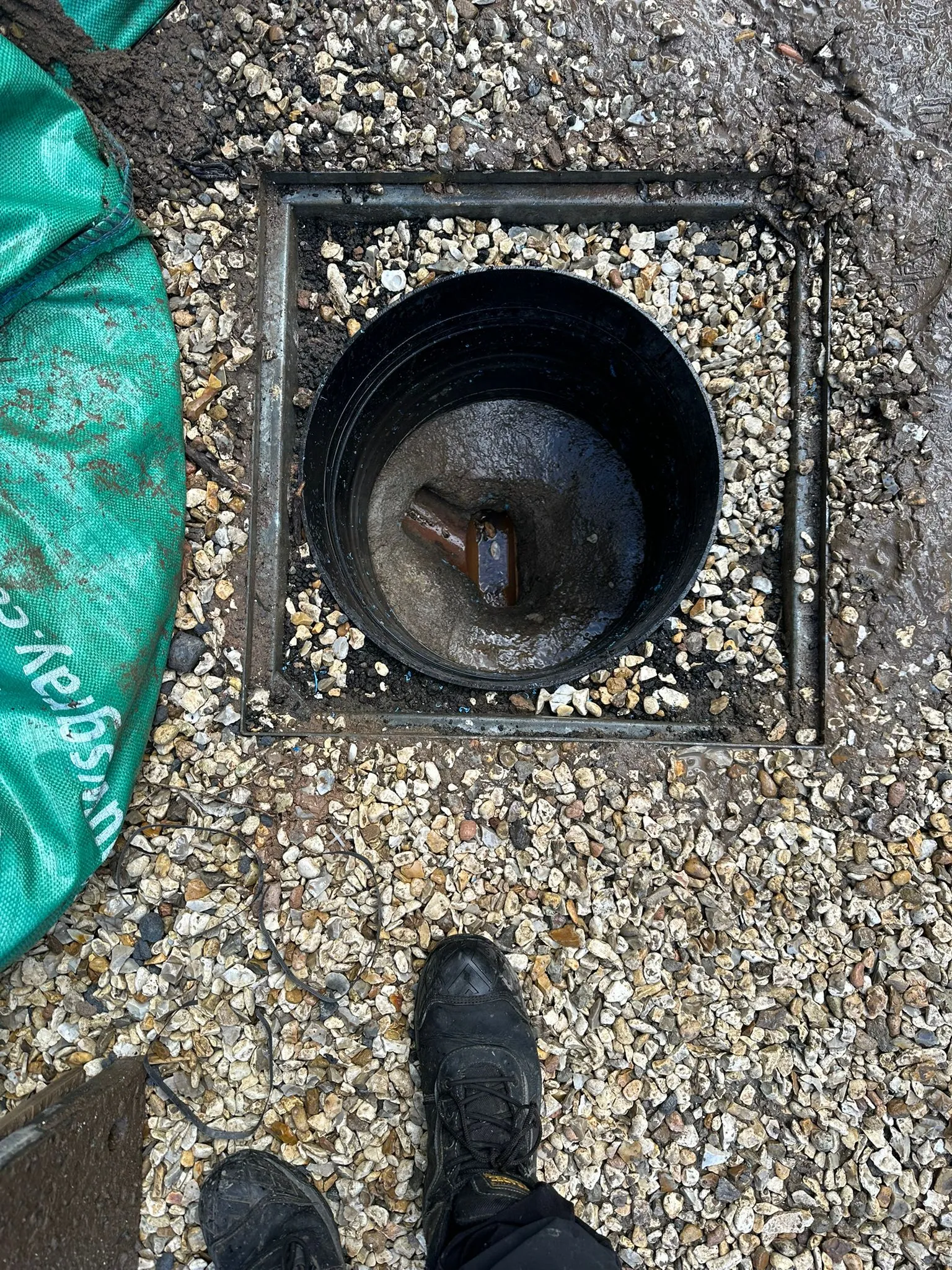 Engineer's view of an open outdoor drain access point during an inspection.