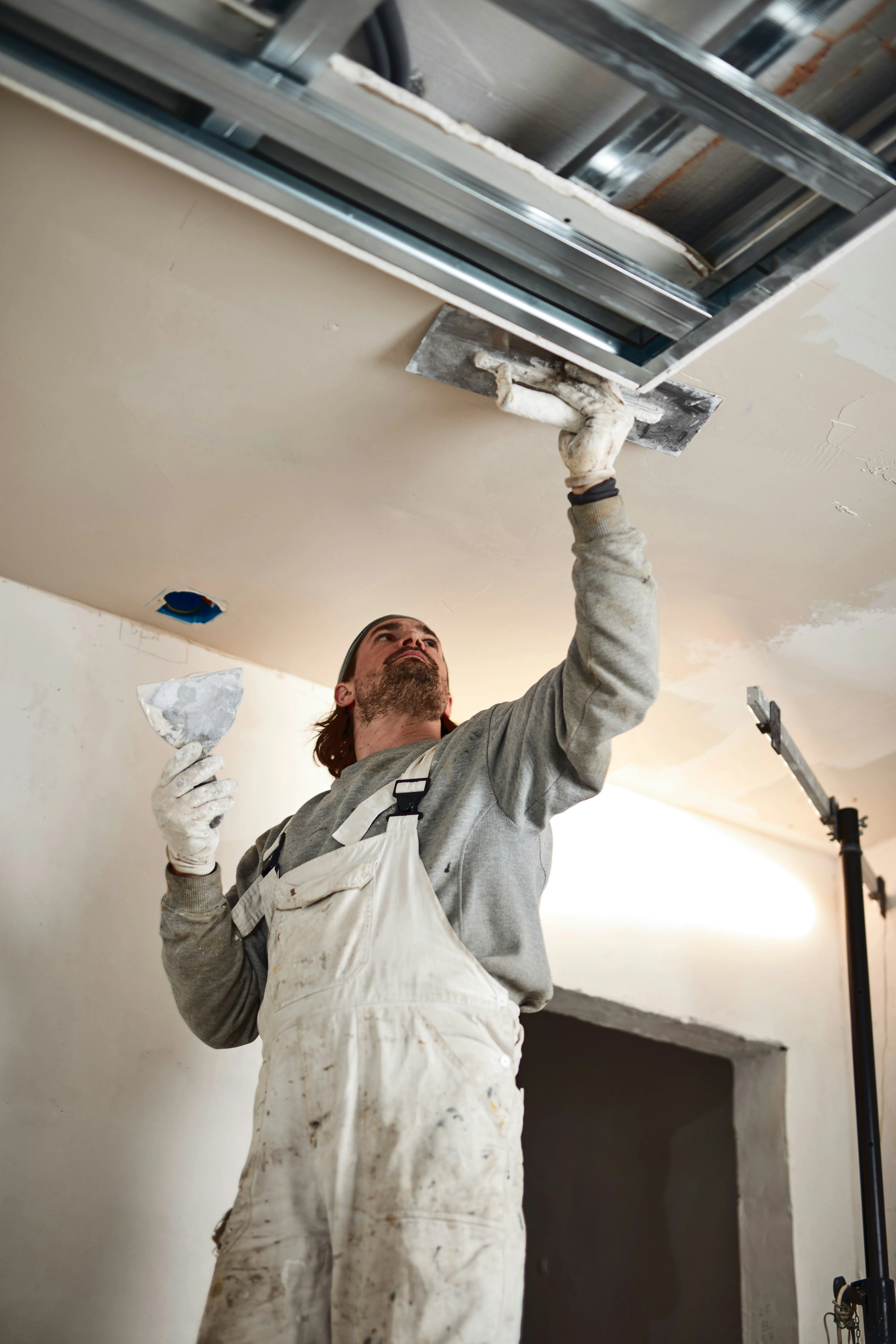 Skilled plasterer applying plaster to a ceiling in a Haywards Heath property.