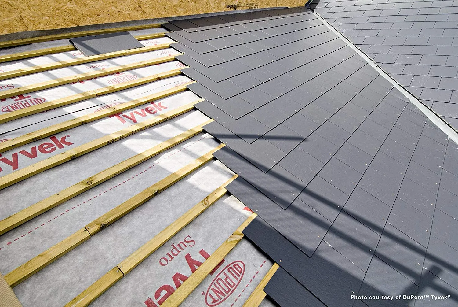 Pitched roof installation in progress with tiles, underlayment, and battens