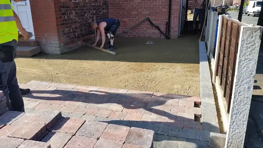 Workers installing block paving for a new driveway or patio project.