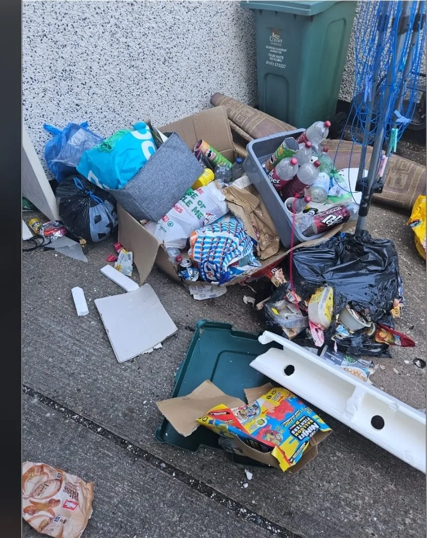 A messy outdoor area with a large pile of assorted household rubbish and waste, indicating a need for rubbish removal services.