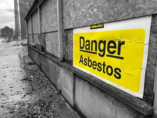 Danger Asbestos sign on an old industrial building, highlighting the presence of hazardous materials.