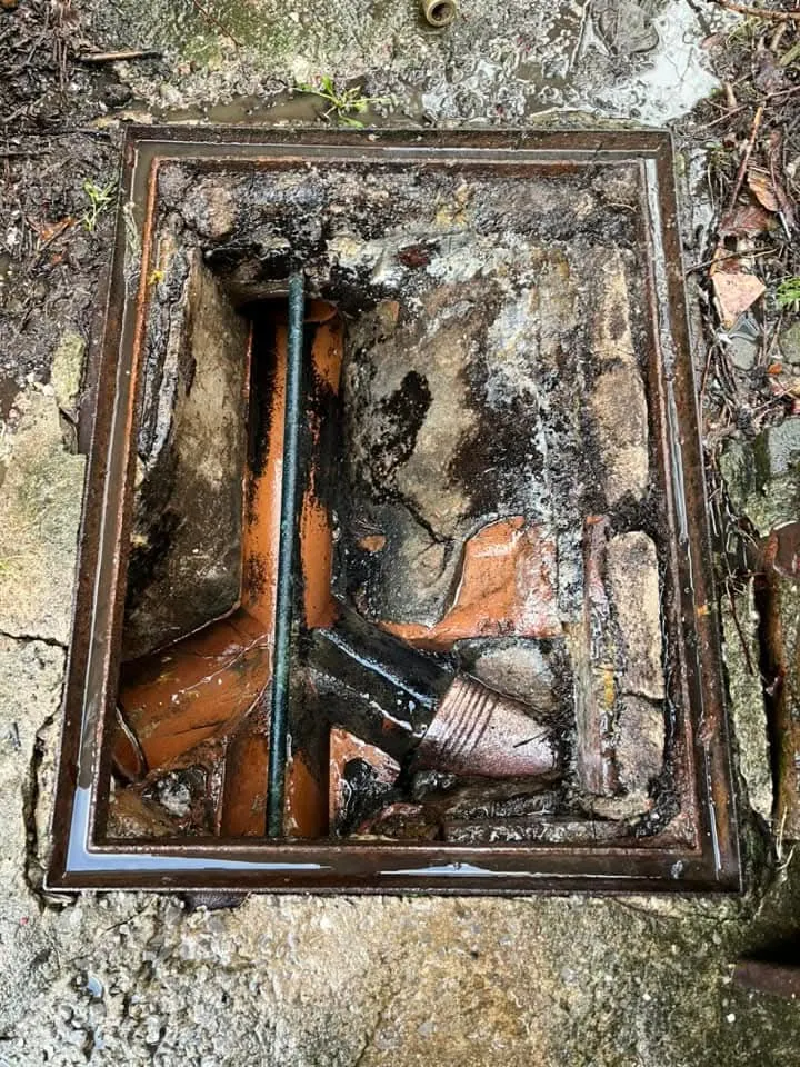 An open manhole cover showing underground drainage pipes.
