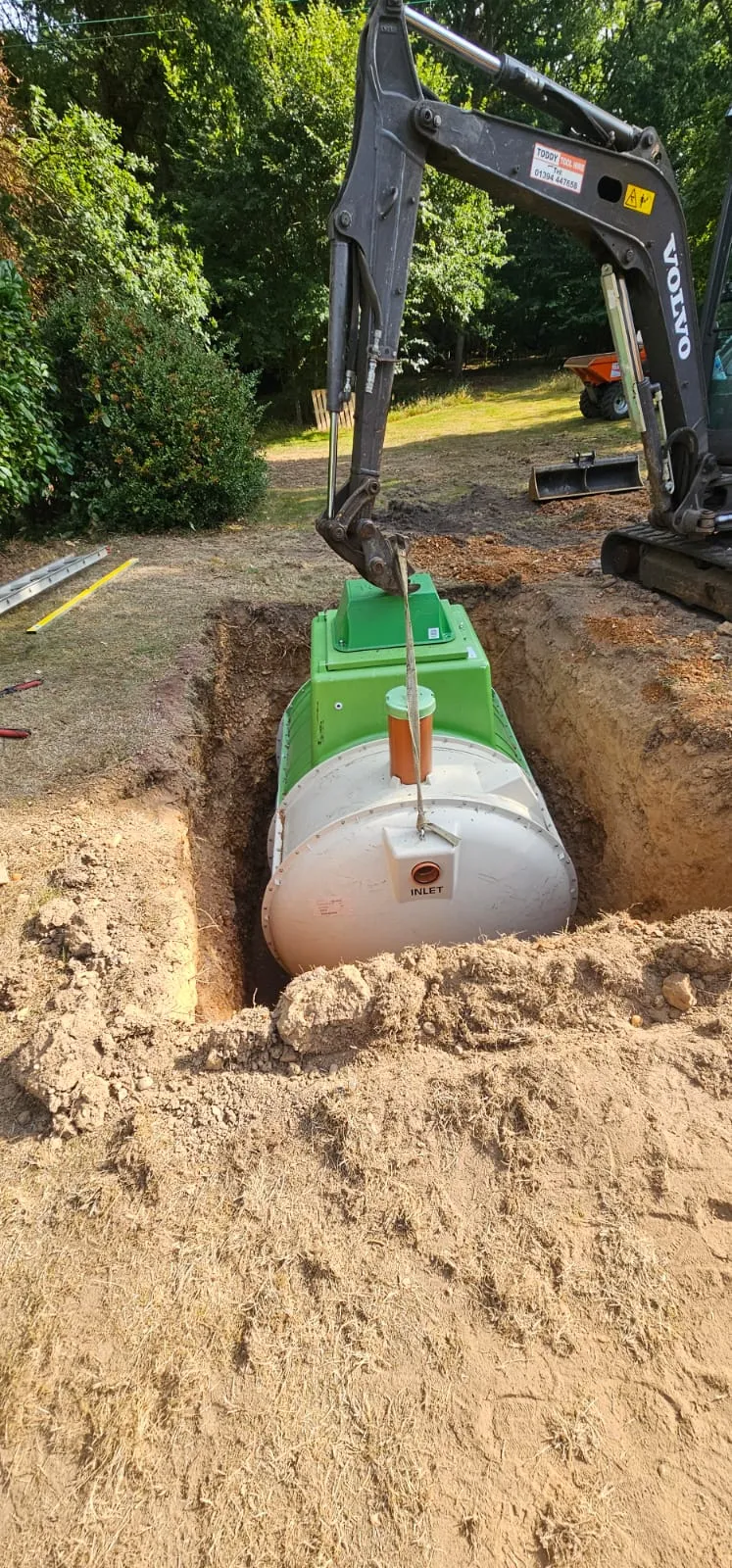 Excavator installing a new septic tank or sewage treatment plant in the ground.