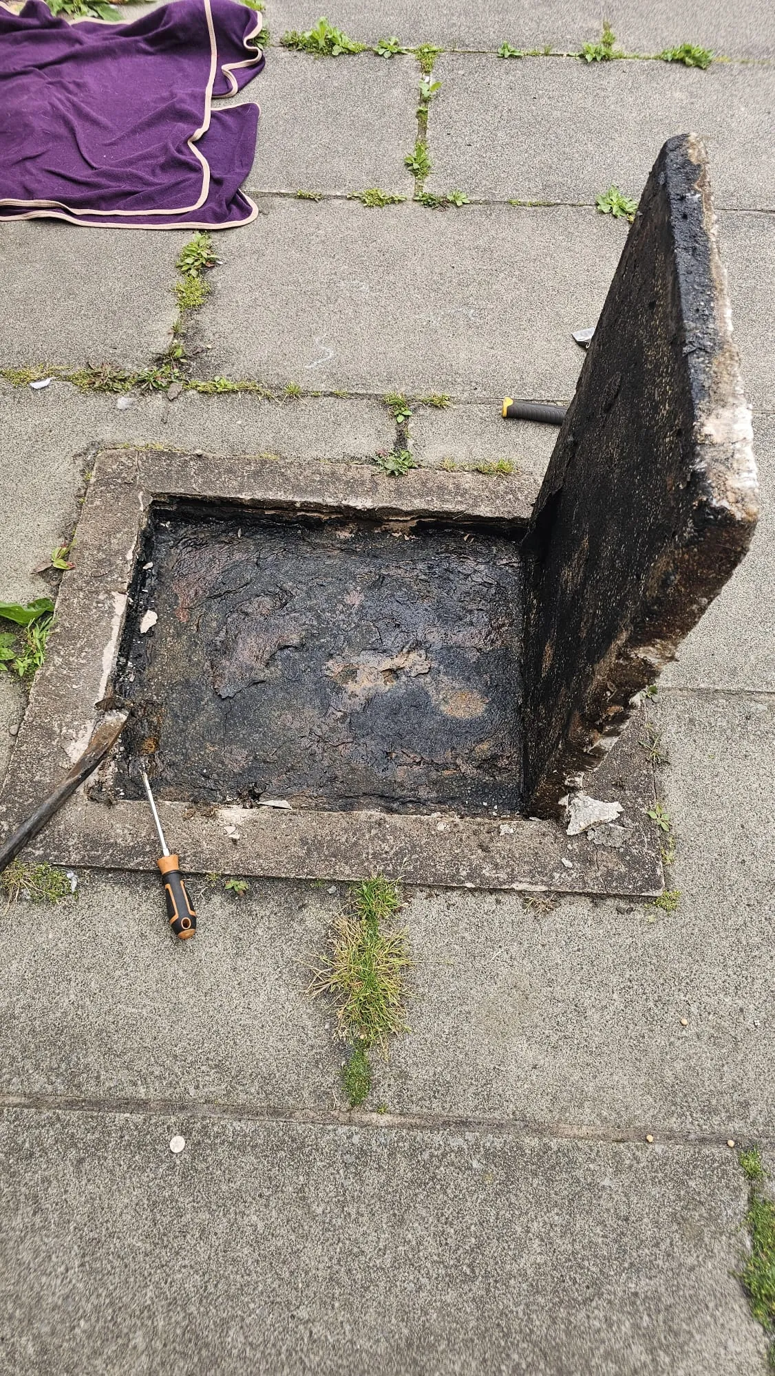 A severely blocked drain or manhole full of dark, thick sludge.