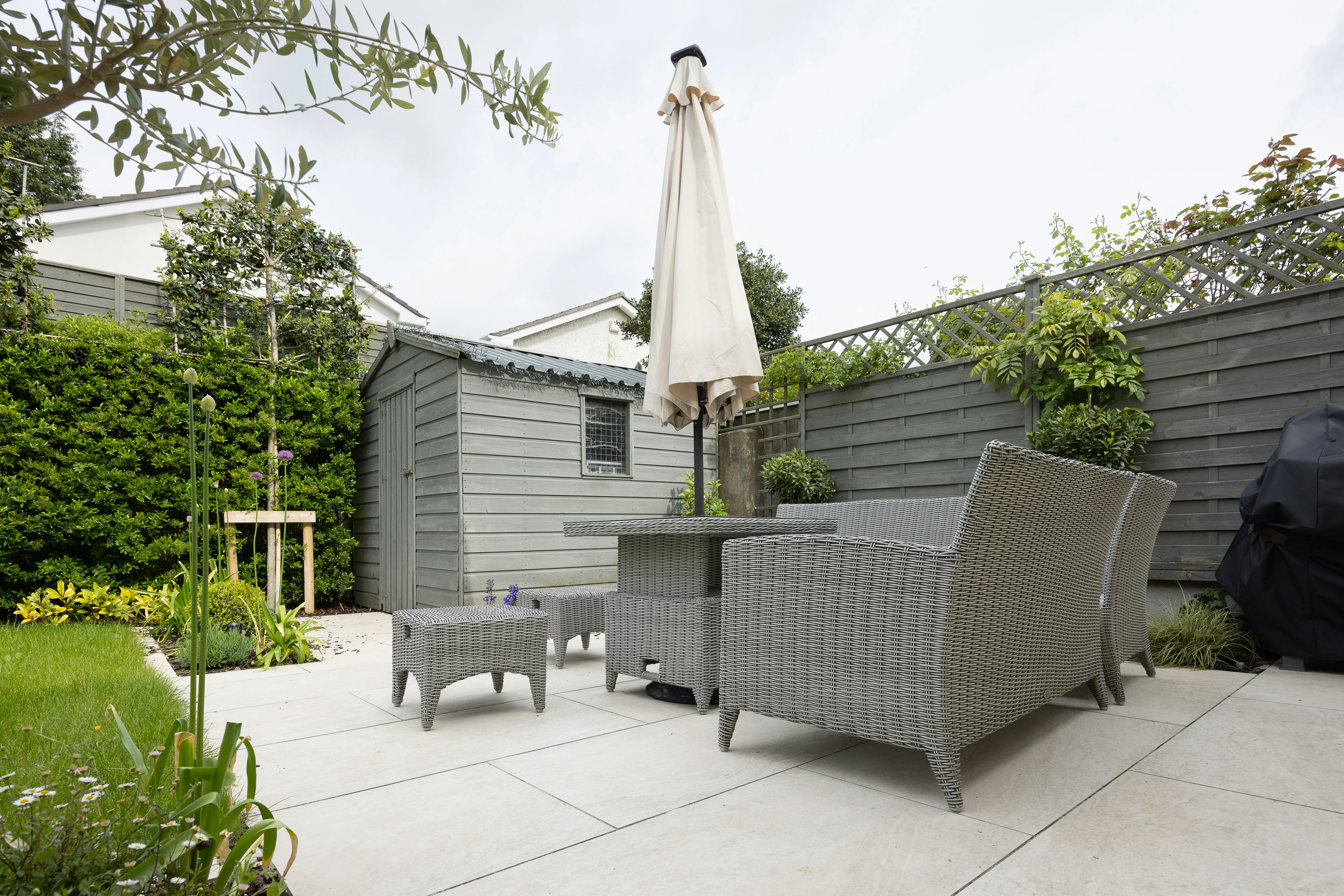 Modern garden patio with paving slabs, outdoor furniture, and shed
