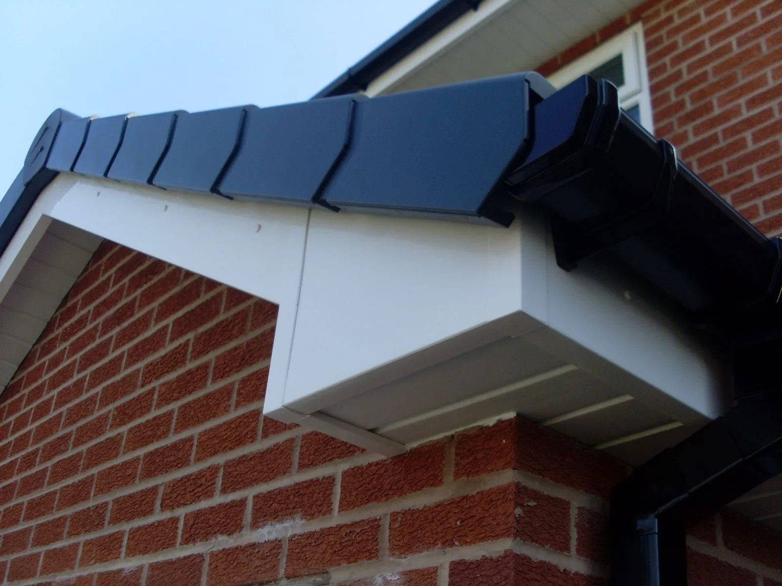 Professional installation of black guttering, white fascia, and soffit.