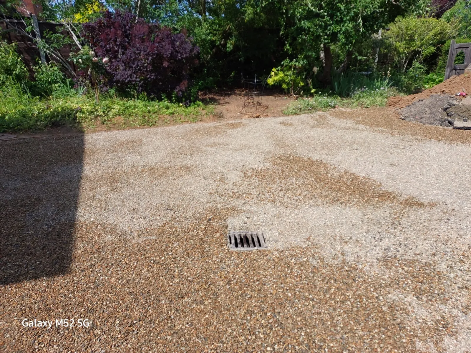 A surface water drain grate on a gravel driveway.
