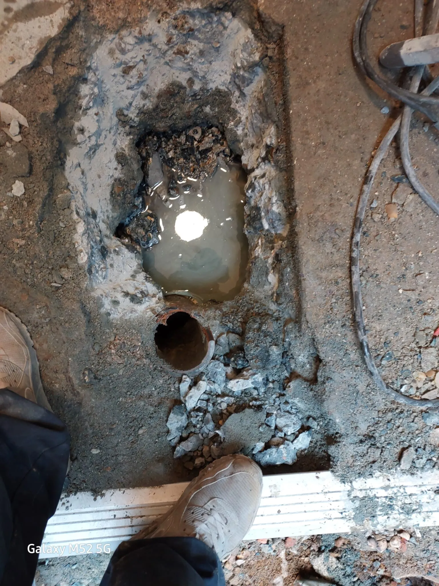 Excavated ground showing a damaged drain pipe submerged in dirty water, signalling a need for professional drain repair.