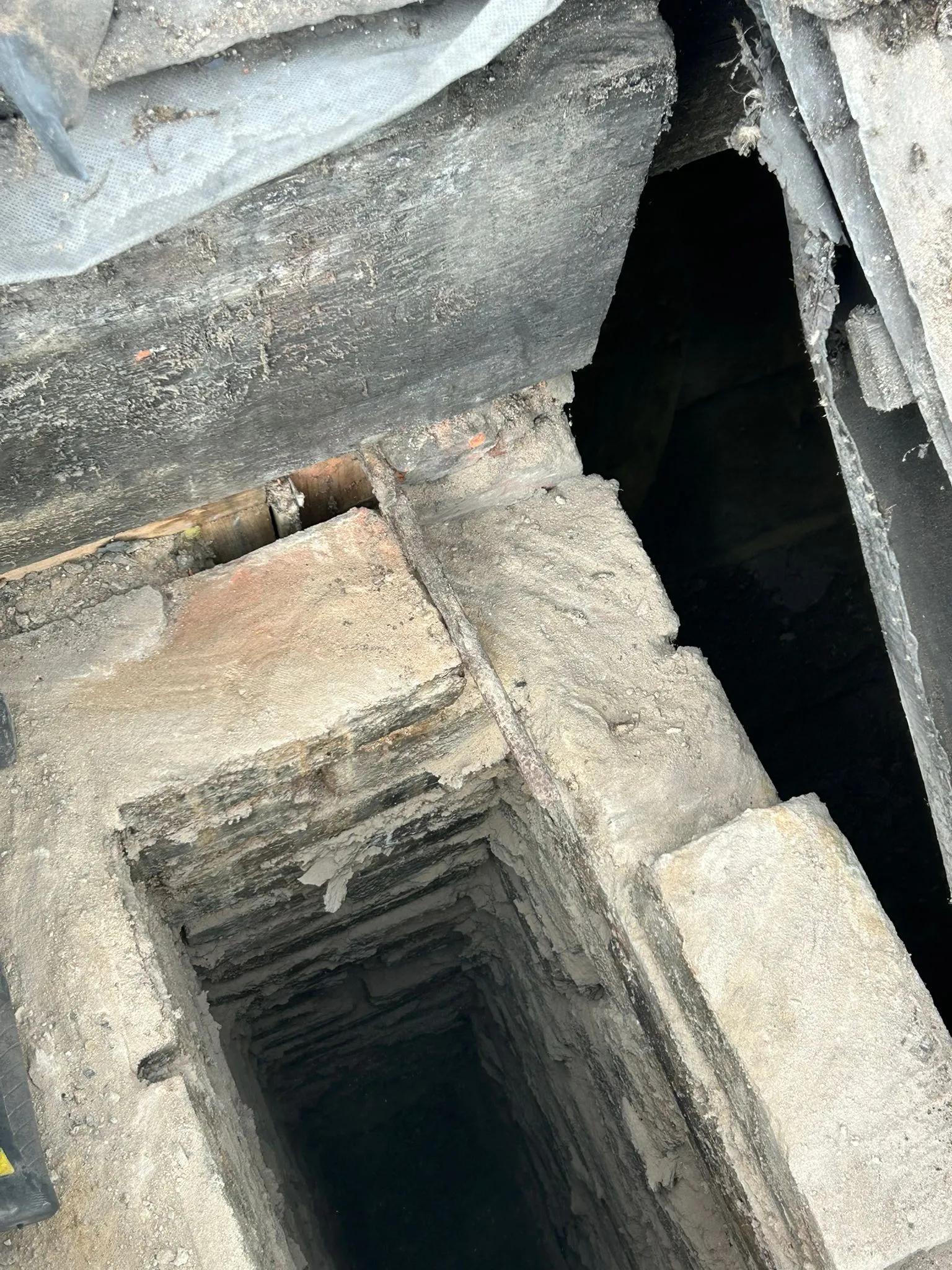 Close-up of a chimney flue opening with crumbling mortar and brick damage.