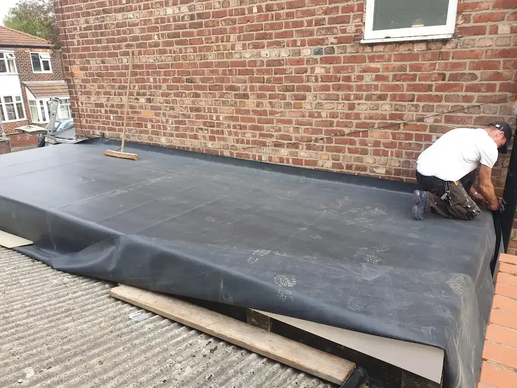 Roofer installing flat roof membrane in Manchester