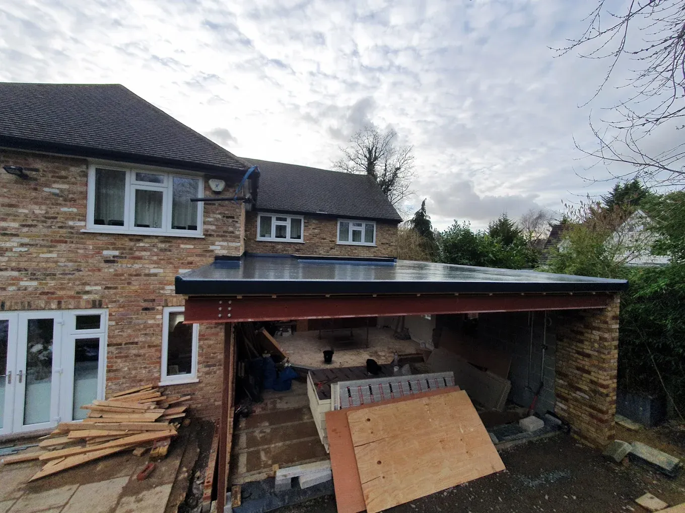 Newly installed flat roof on a house extension in Oxfordshire, showing steel supports and building materials.