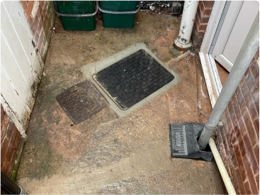 Exterior drainage system with manhole covers and a downpipe at a residential property