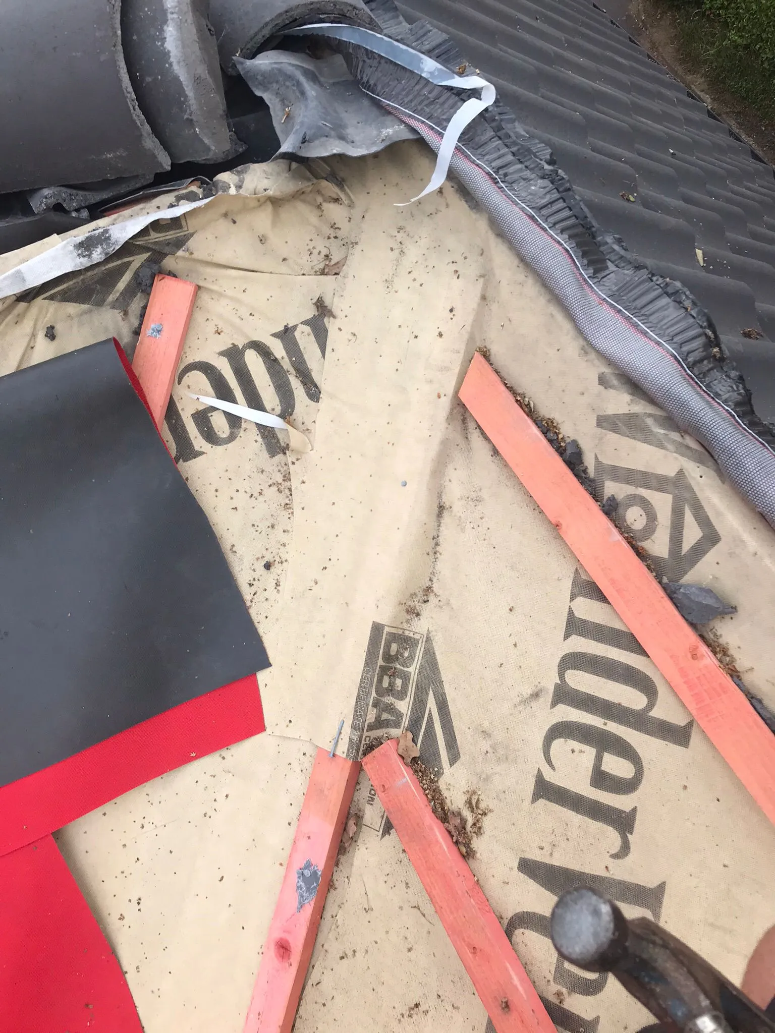 Close-up of roof construction showing underlayment, battens, tiles, and membrane.