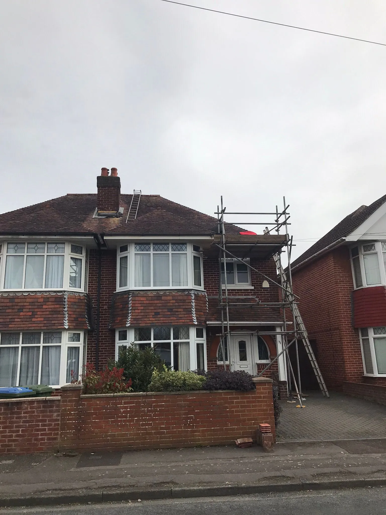 Scaffolding set up for roof repair on a traditional brick semi-detached house.
