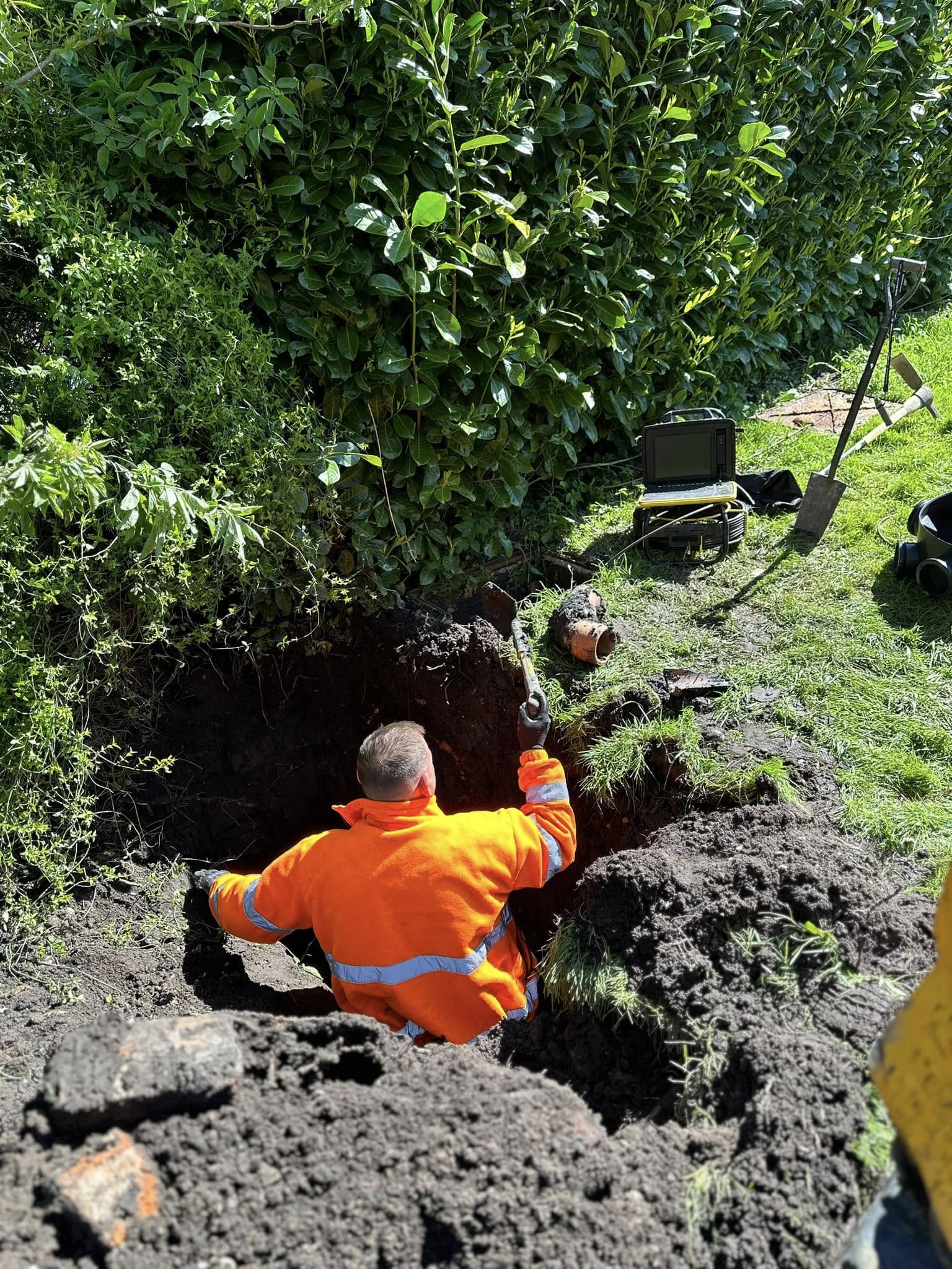 Drainage engineer in an excavated trench with CCTV camera for drain repair