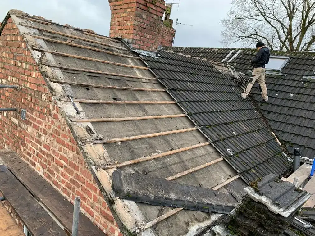 Roofers working on a tiled residential roof, replacing old tiles.