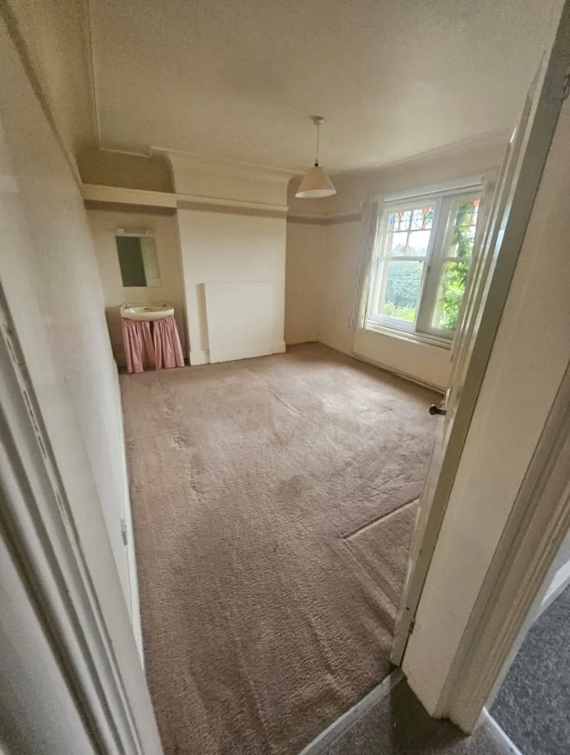 Empty bedroom or living room with carpet and a small sink, ready for end-of-tenancy or full house clearance by a professional team.