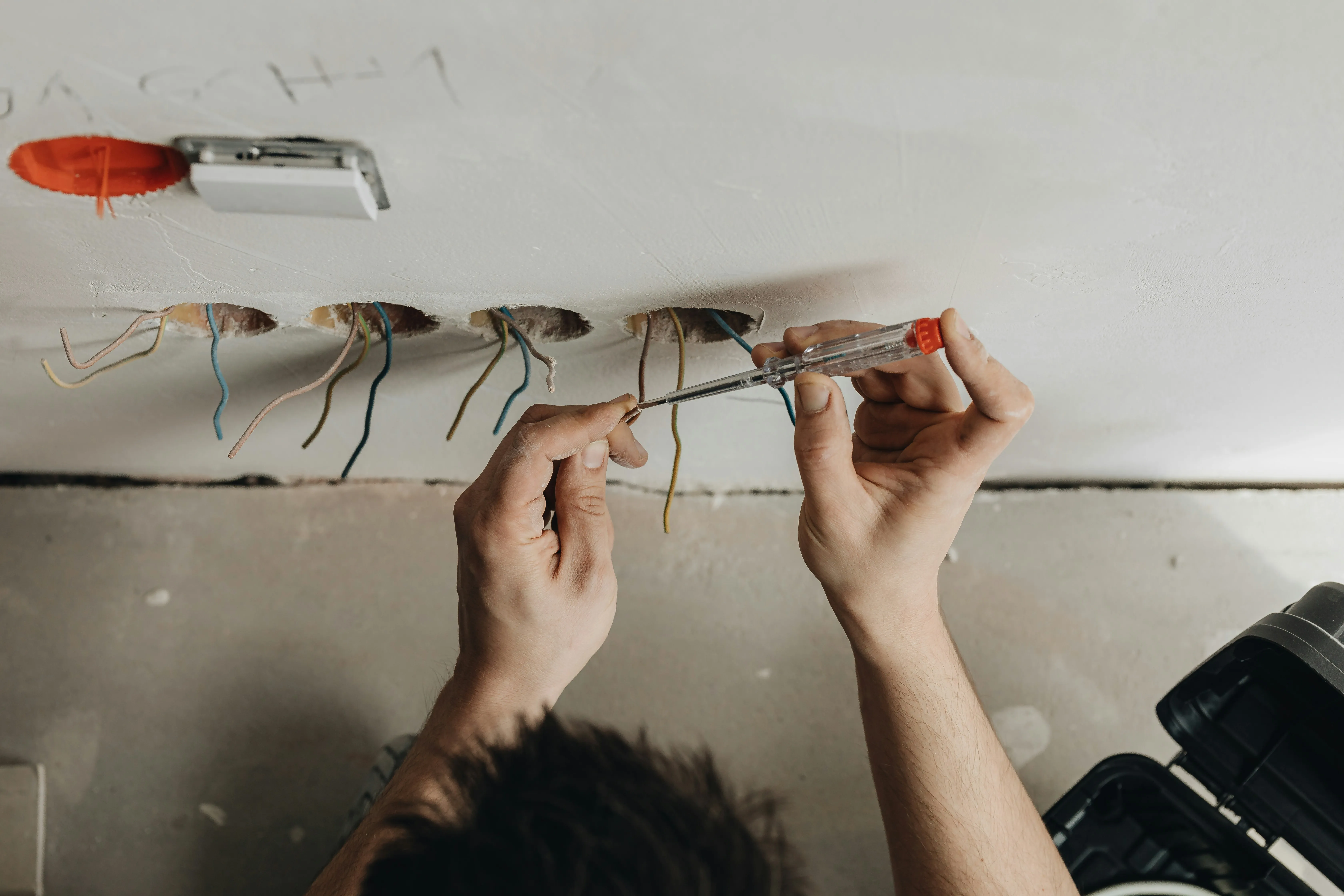 Electrician testing electrical wires in a wall for new socket installation or rewiring