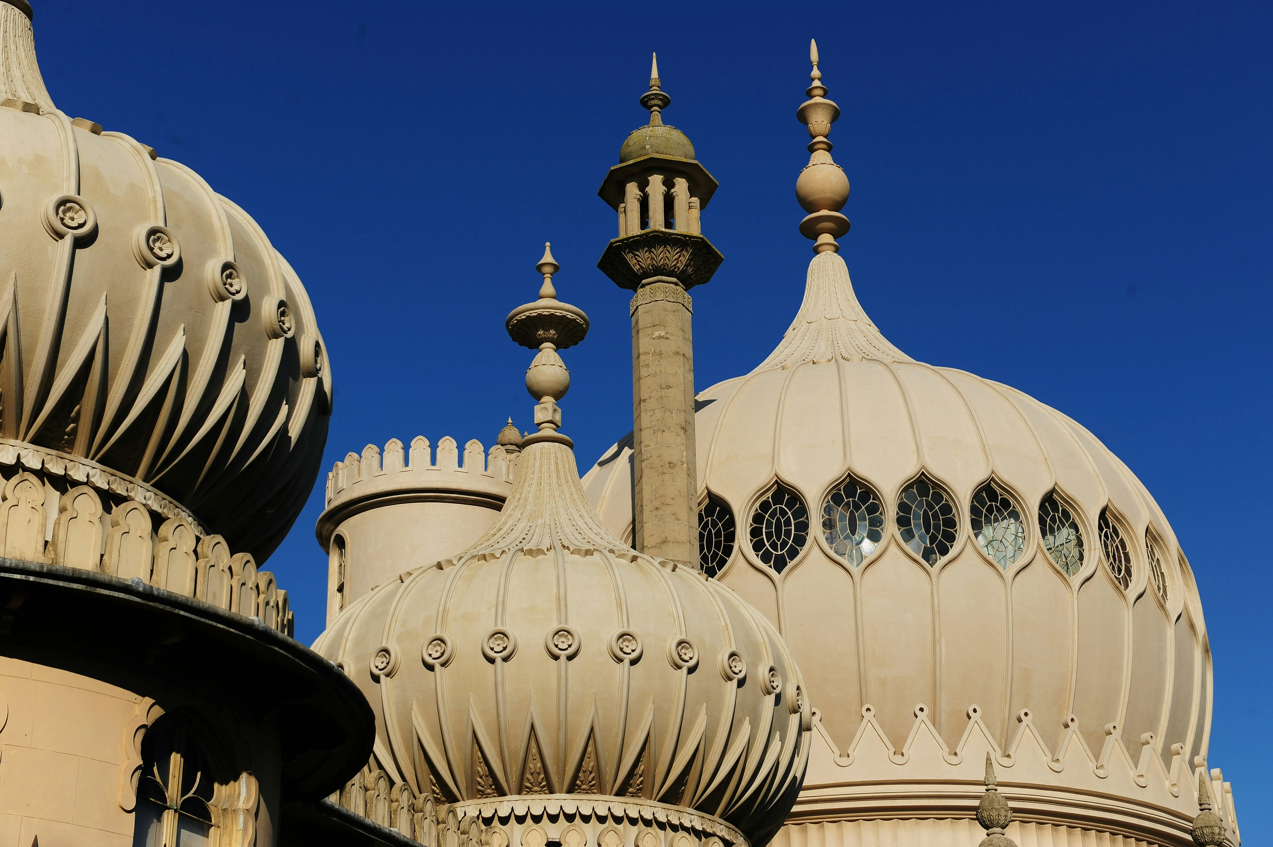 Close-up view of the ornate domes and spires of the Royal Pavilion in Brighton against a blue sky.
