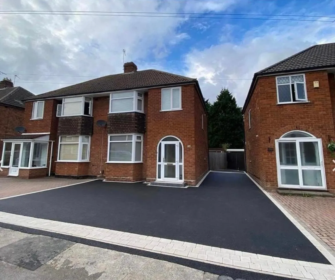 Newly laid tarmac driveway with block paving edging in front of a residential house.