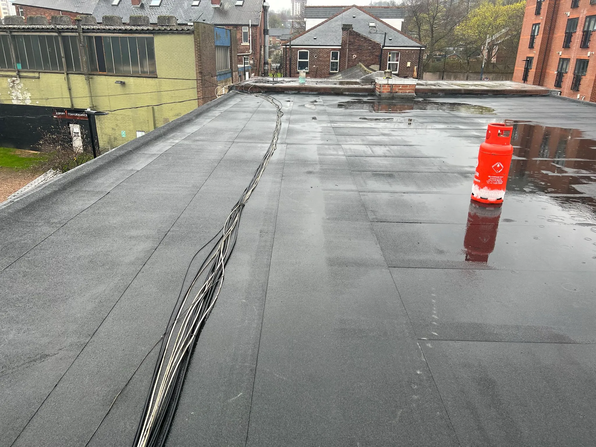 Flat roof with water, cables, and gas bottle.