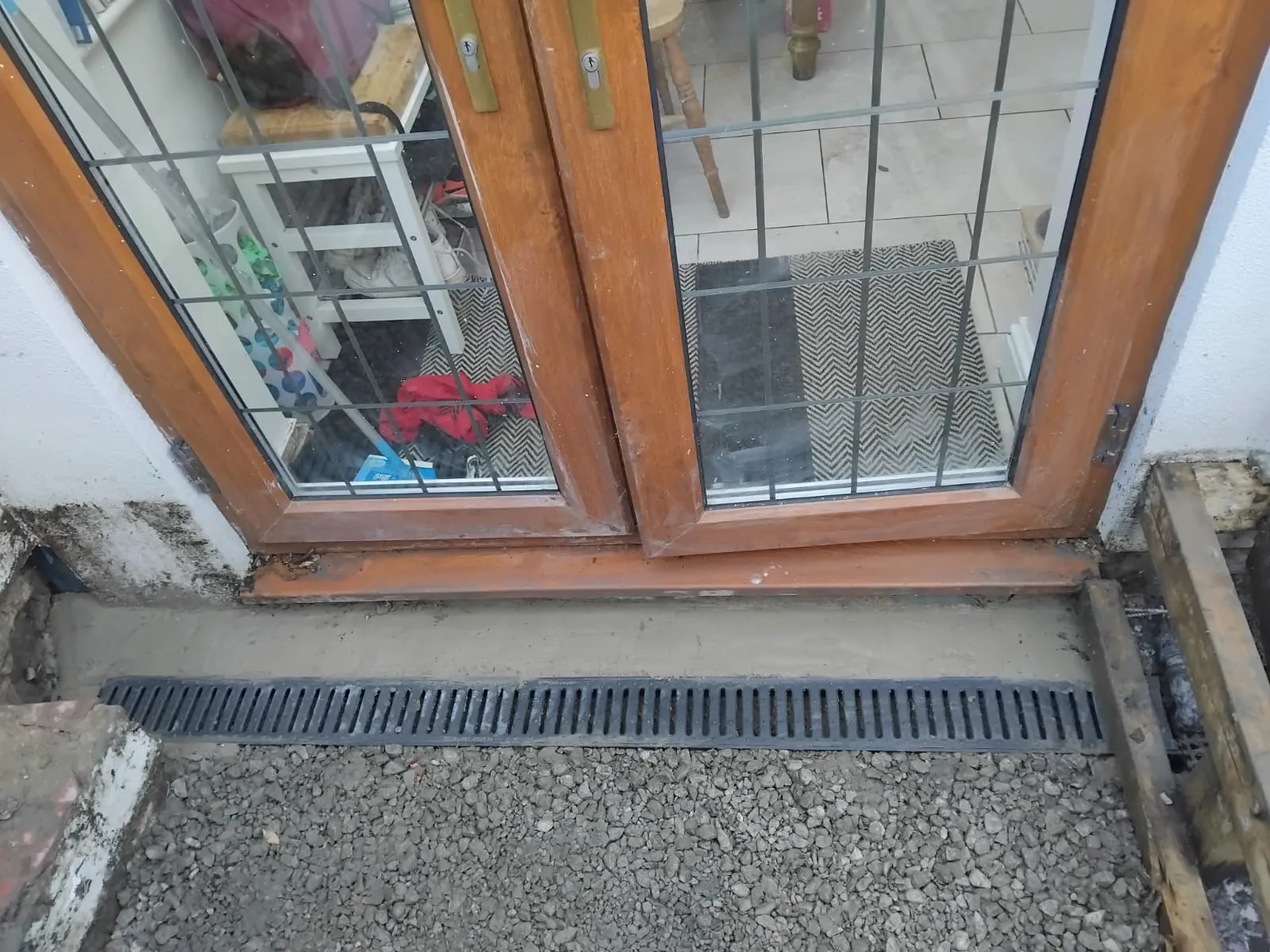 Newly installed linear channel drain for surface water drainage in front of residential patio doors.