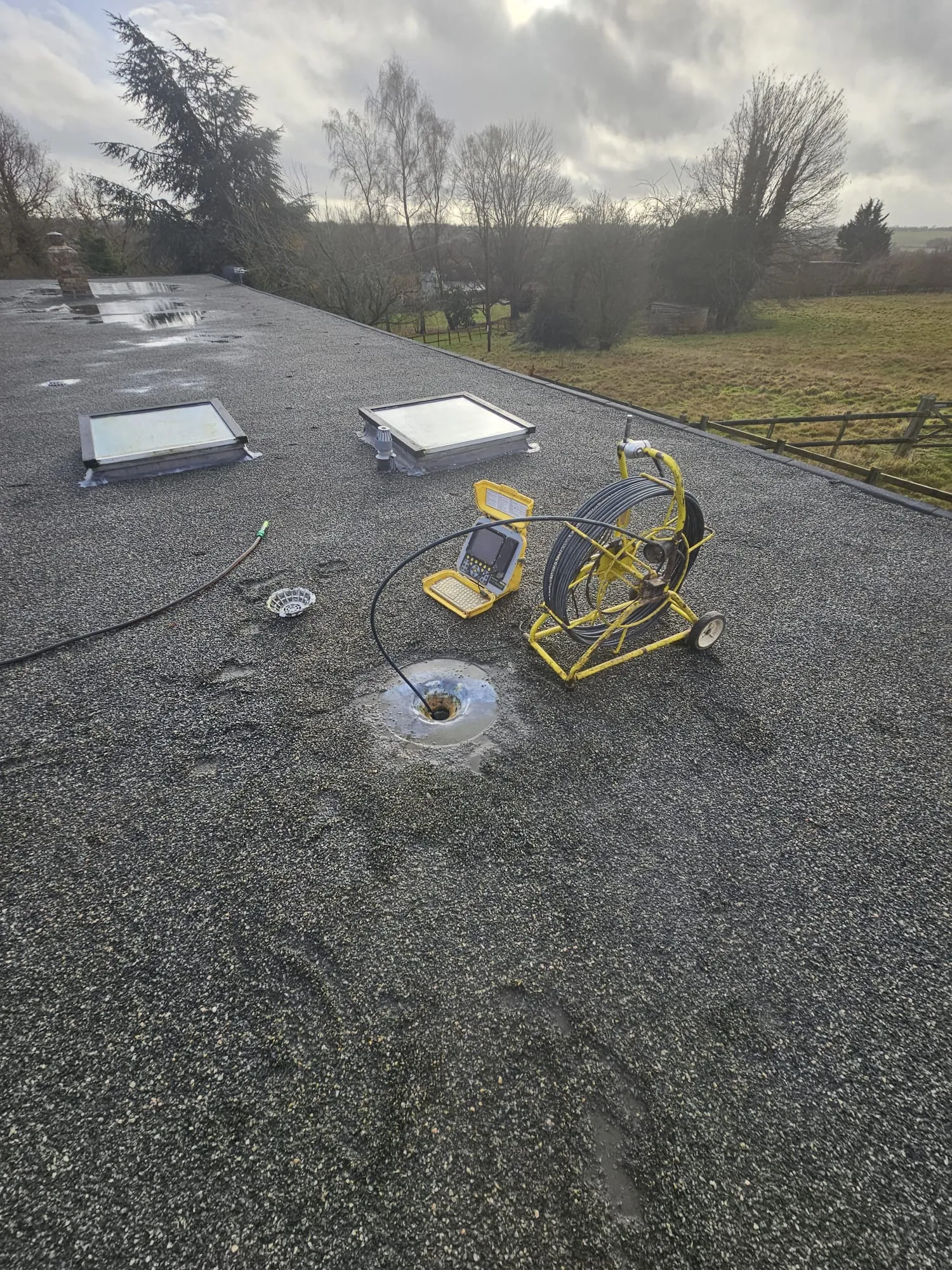 CCTV drain survey equipment set up on a flat roof, with the camera cable entering a roof drain to diagnose potential issues in Ipswich, Suffolk.