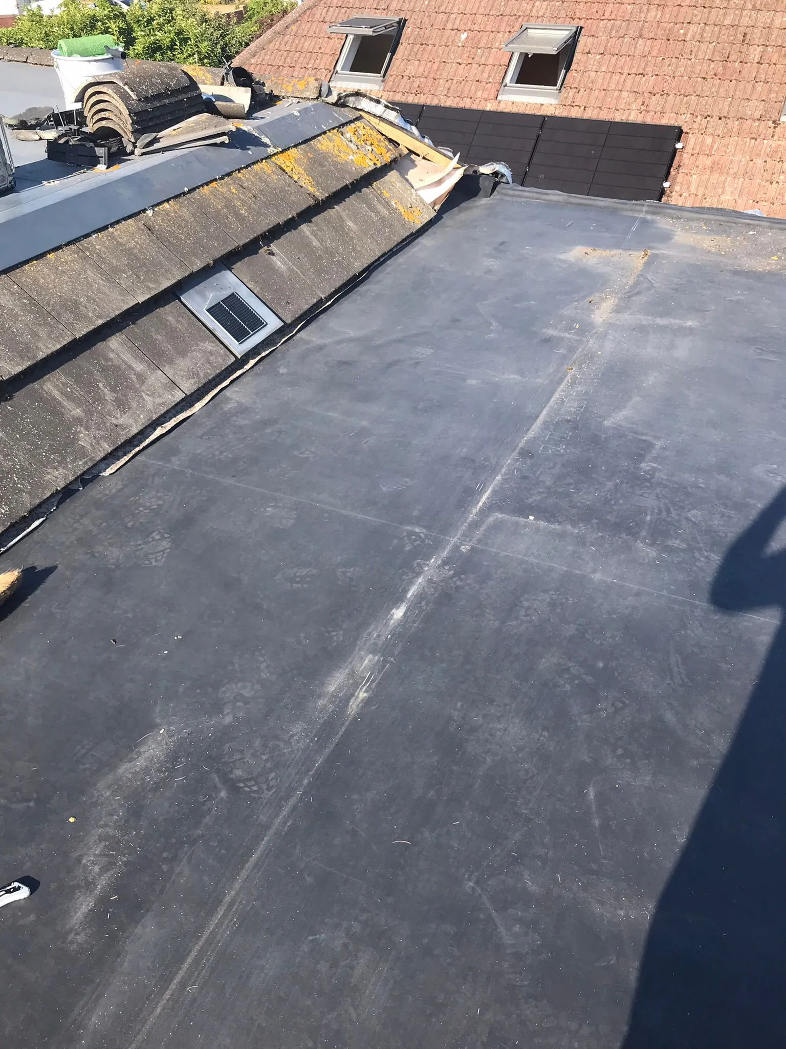 Transition area between a flat roof and a pitched tile roof with a solar vent on a residential property.