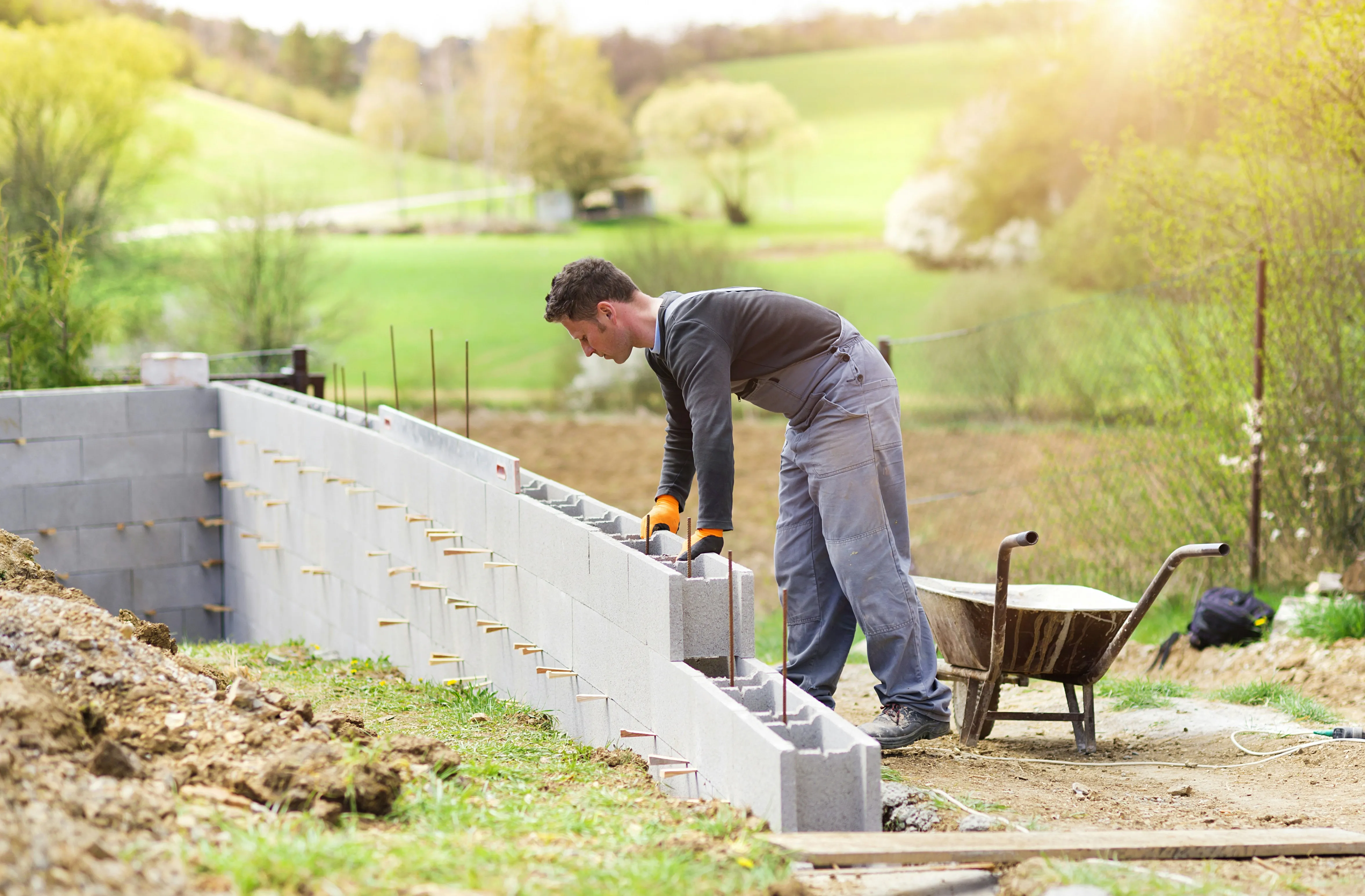 Builder laying concrete blocks for a wall or foundation outdoors