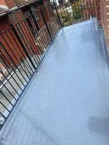 Newly installed grey flat roof on a residential balcony with black metal railings.