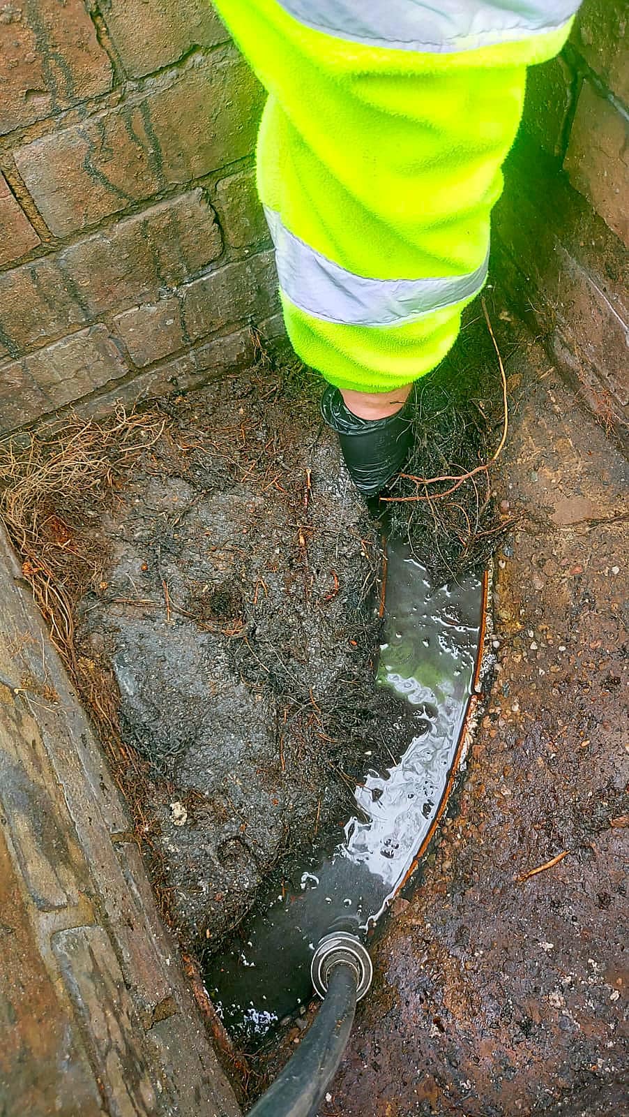 An engineer from Drain 2 Flow Exmouth using high-pressure water jetting to clear a stubborn drain blockage caused by tree roots.