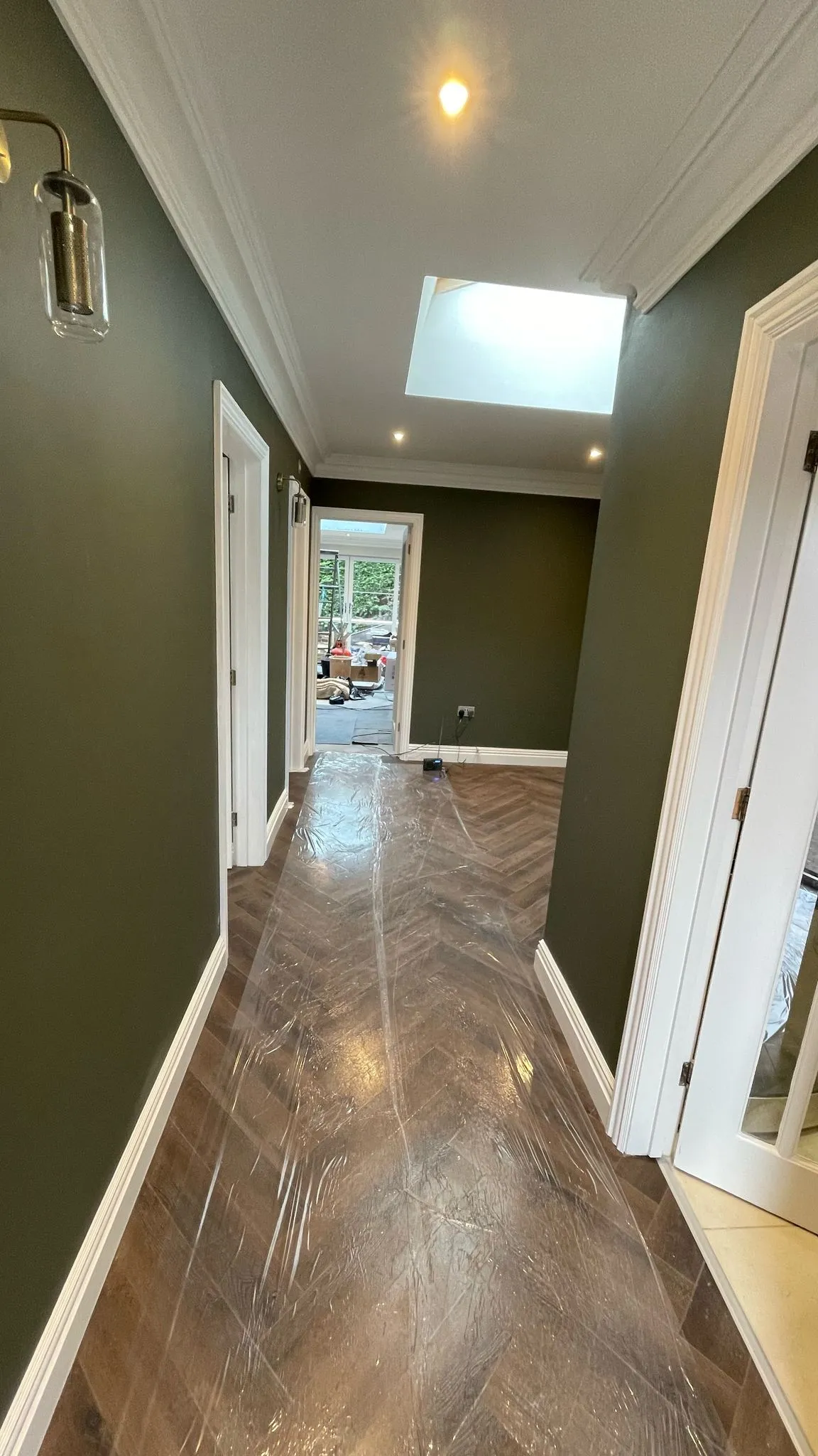 High-quality home renovation showing a hallway with green walls and herringbone flooring in Cheltenham.
