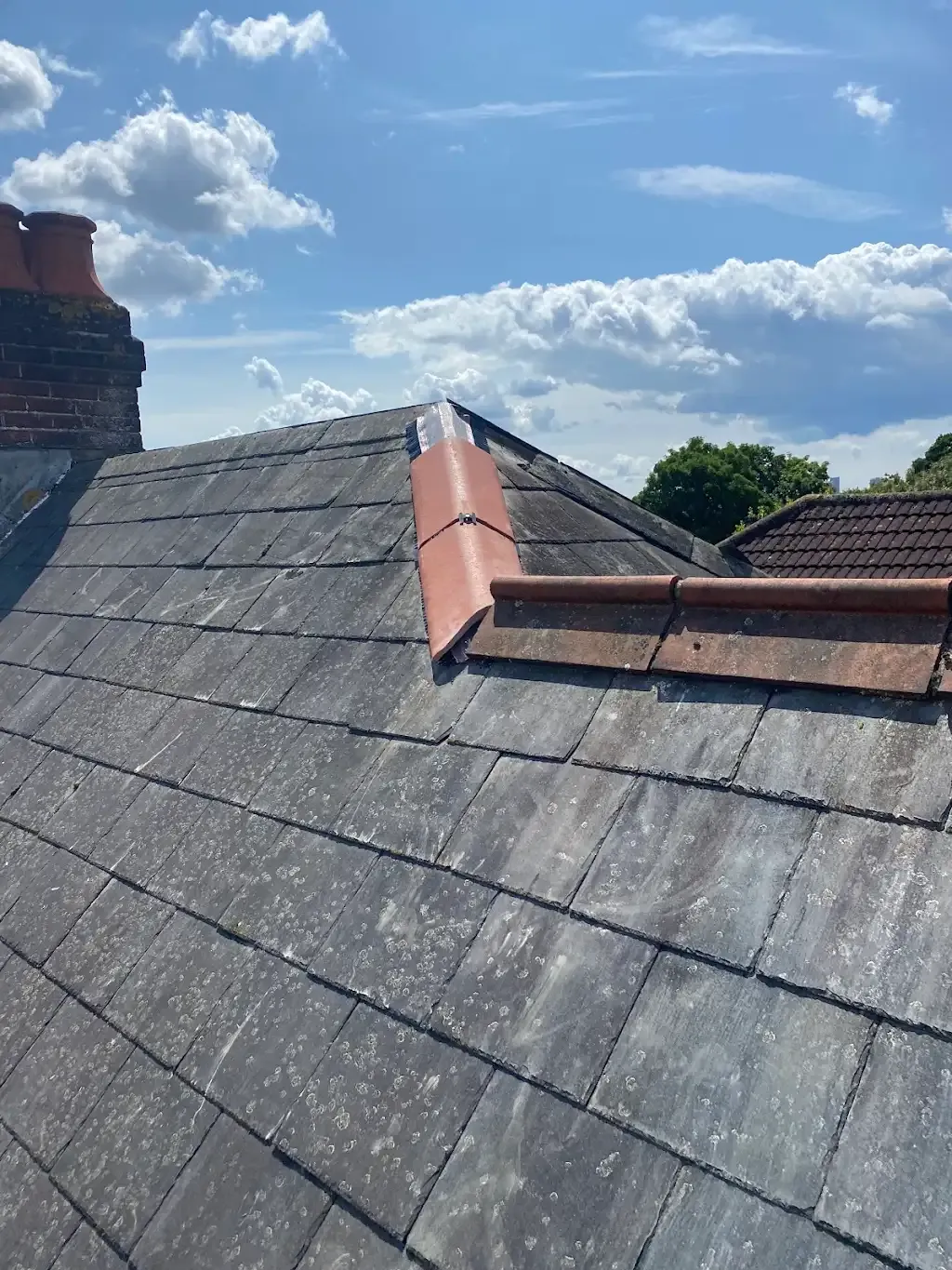 Weathered tiled roof showing ridge tiles and chimney