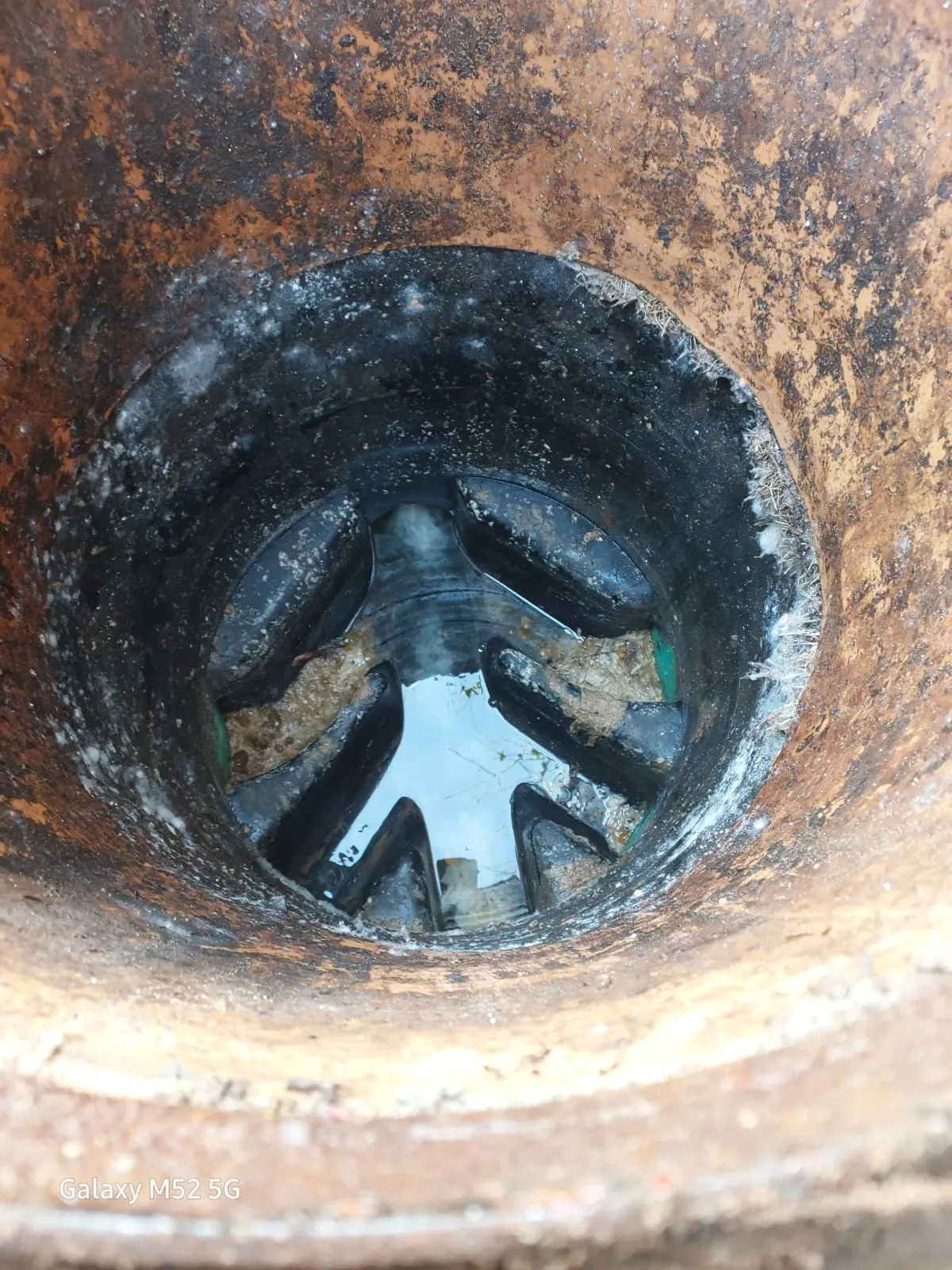 Standing water and debris visible inside a dirty, possibly blocked drain or pipe.