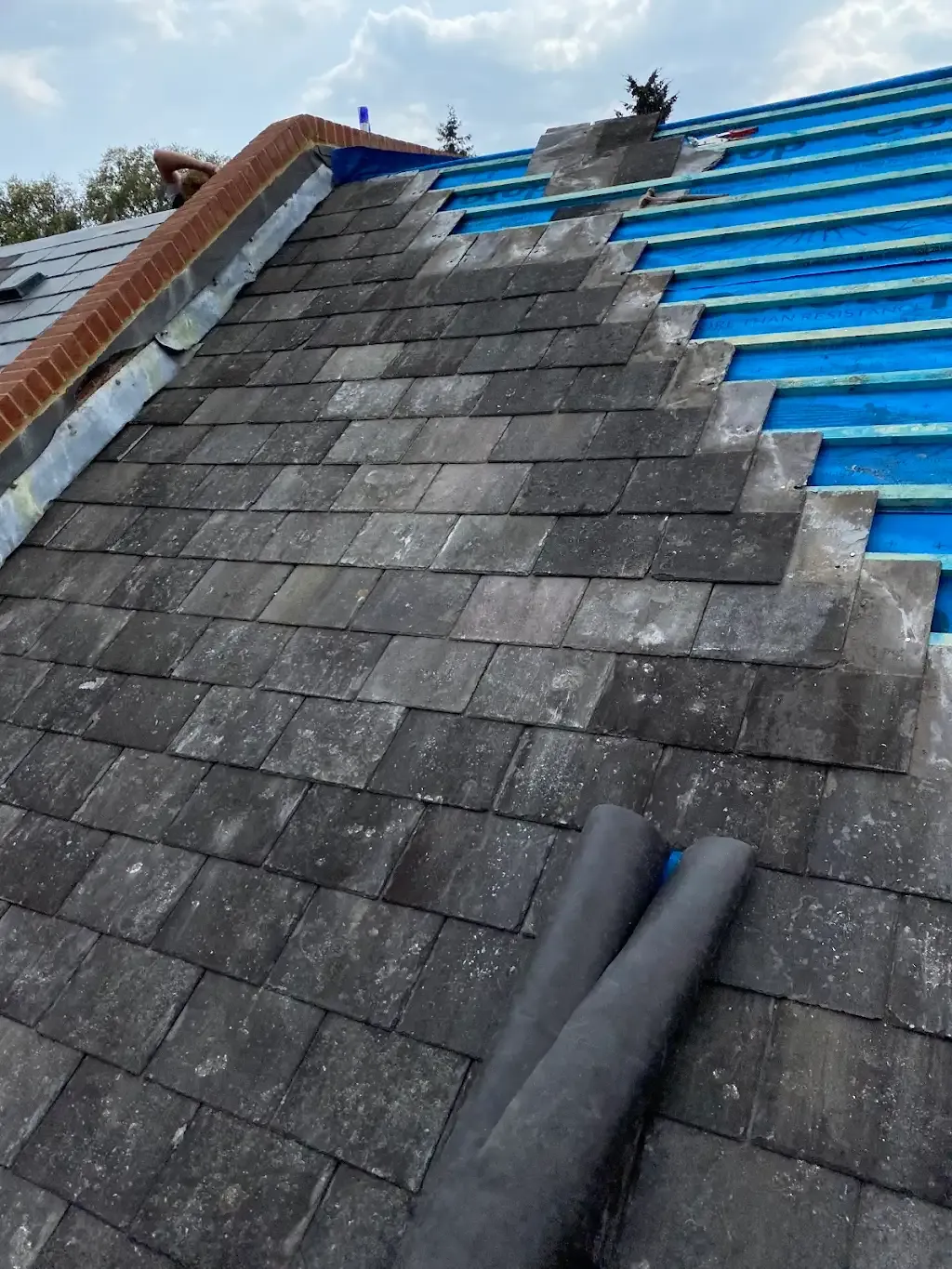 Pitched tiled roof repair or re-tiling in progress.