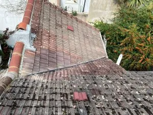 An aged tiled roof heavily covered in moss and grime, indicating a need for cleaning or repair services in Sussex.