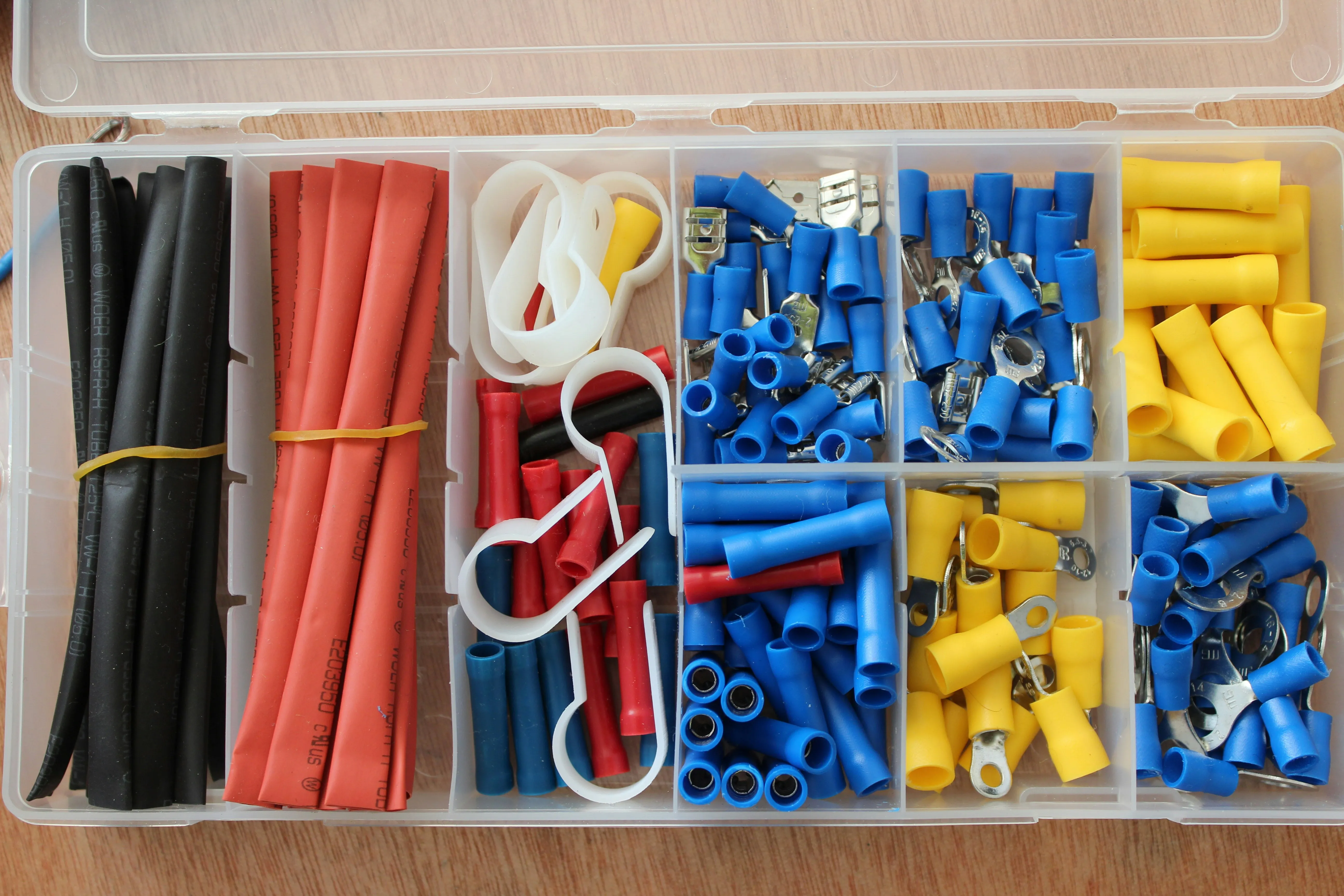 An overhead view of an electrician's kit with colourful electrical connectors, heat shrink tubing, and cable clips, ready for use in installations.