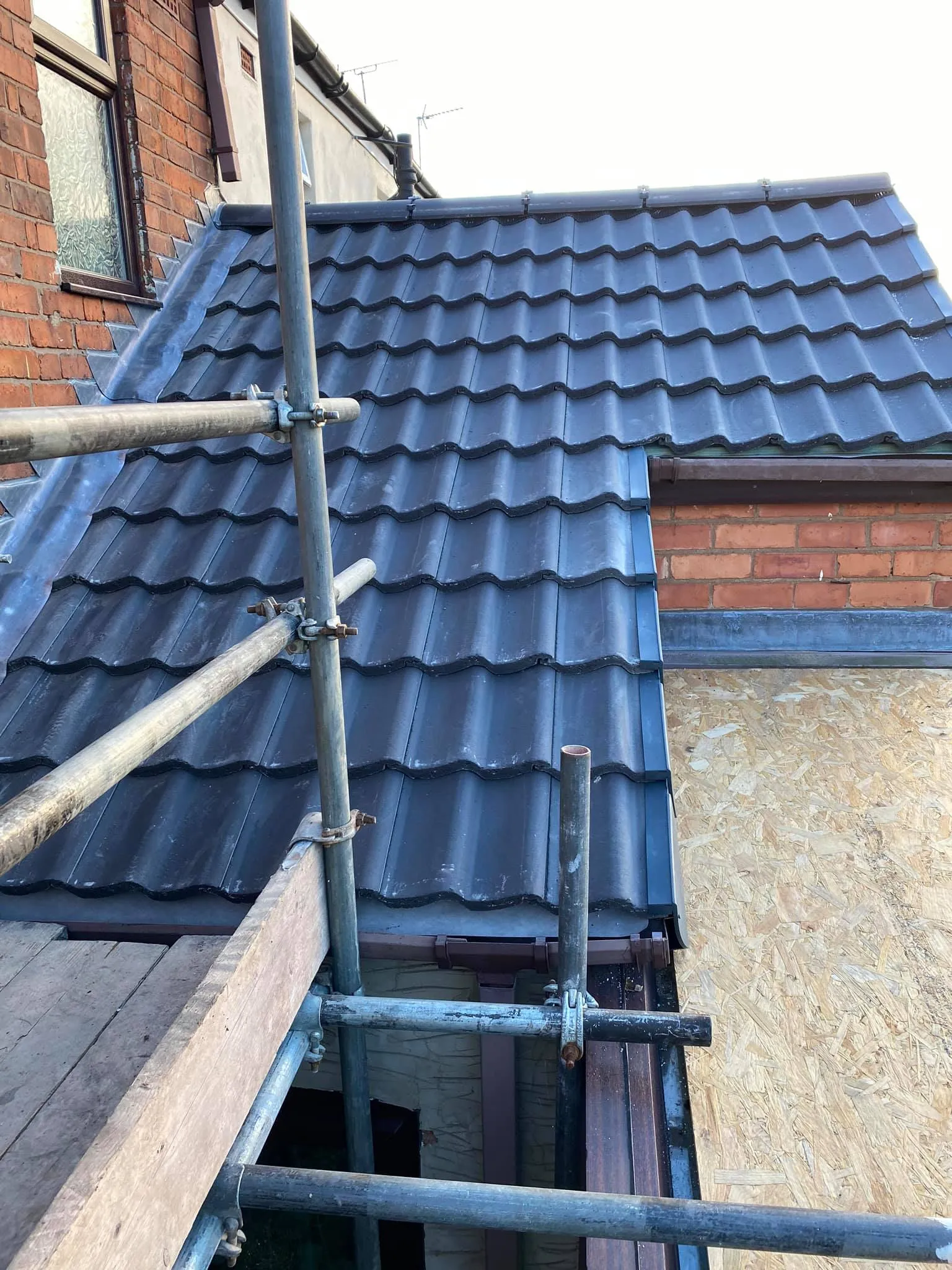 New pitched roof installation with dark tiles and scaffolding