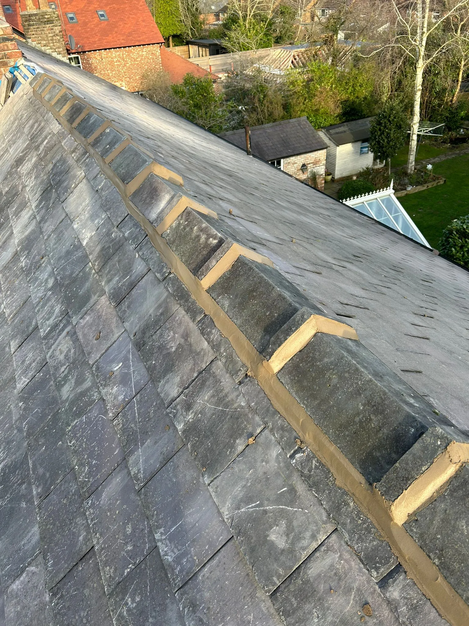Close-up of a slate roof showing new repointing work on the ridge tiles